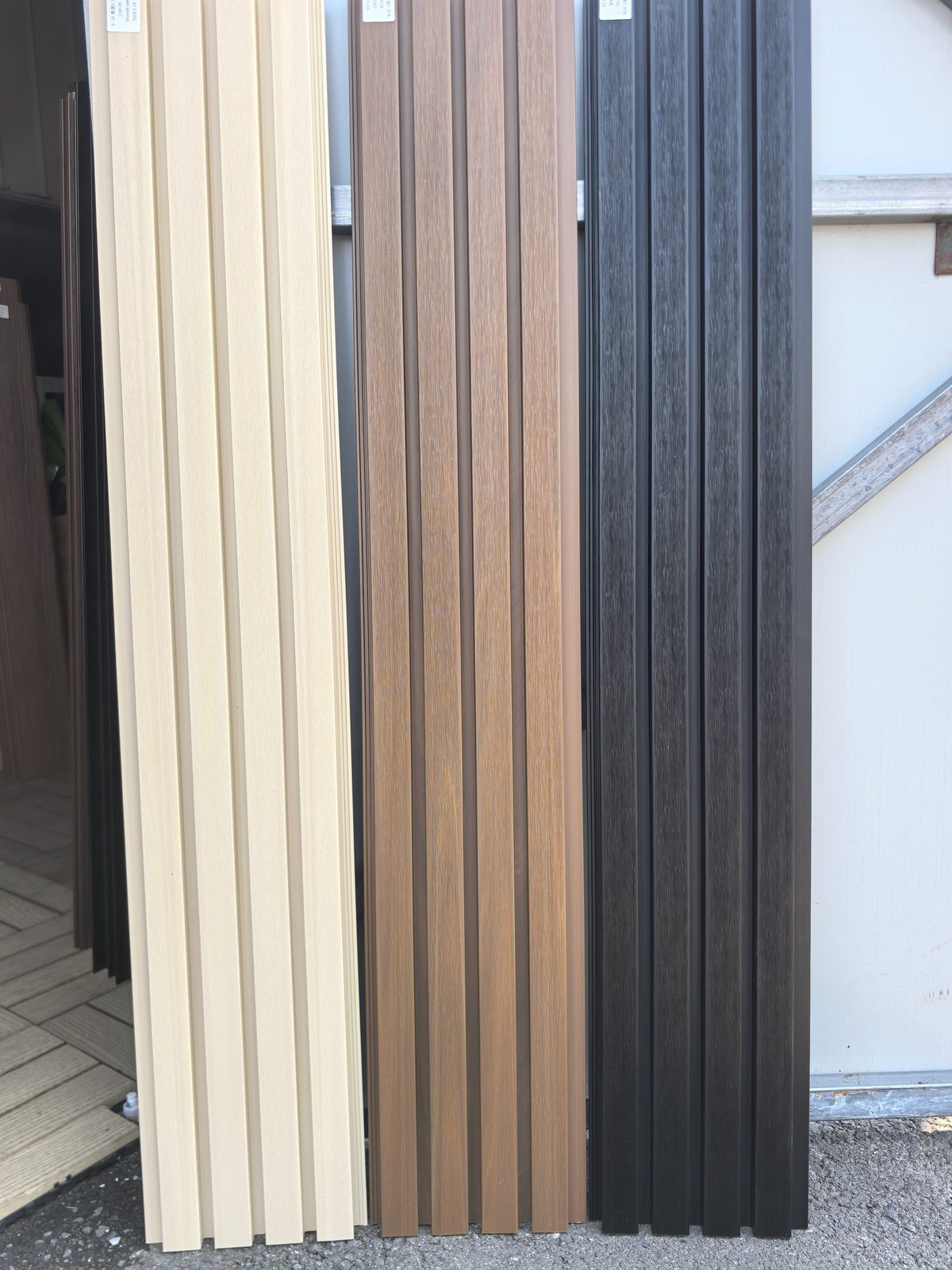 Maple, Teak, and Black WPC cladding boards standing side by side in full length
