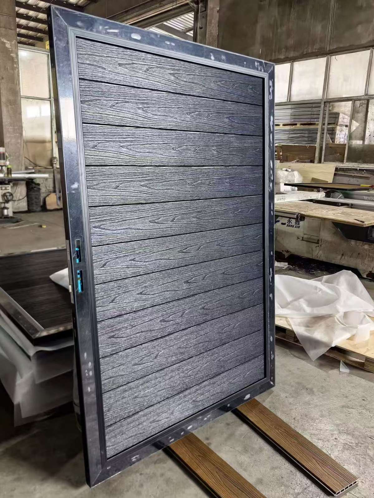 Black WPC gate leaf with aluminum frame showing wood grain texture