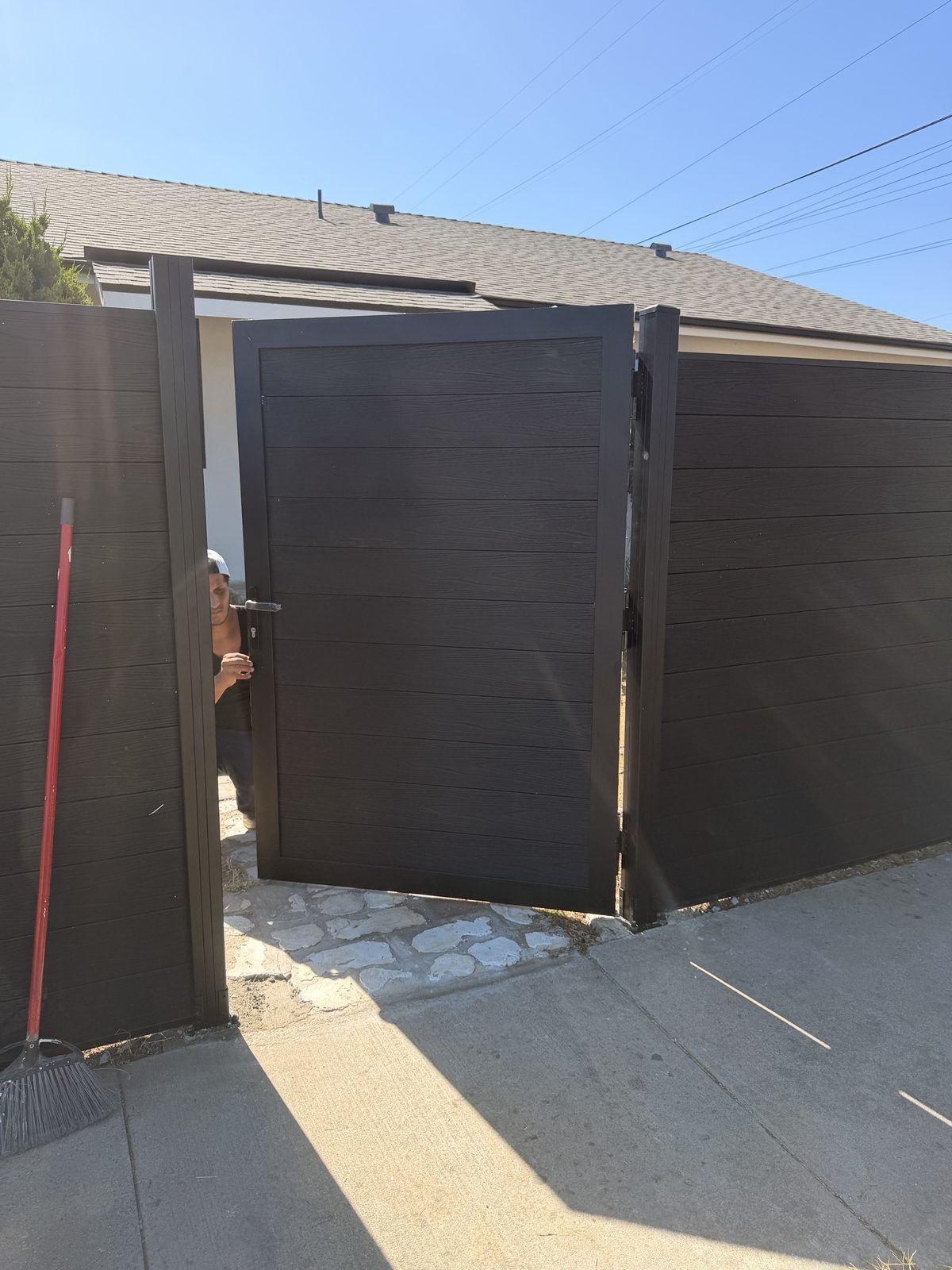 Black WPC privacy gate installed and swung open between two fence bays