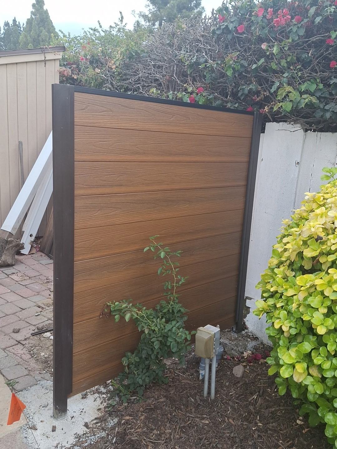 Teak WPC gate installed in a side yard next to an older painted wood fence